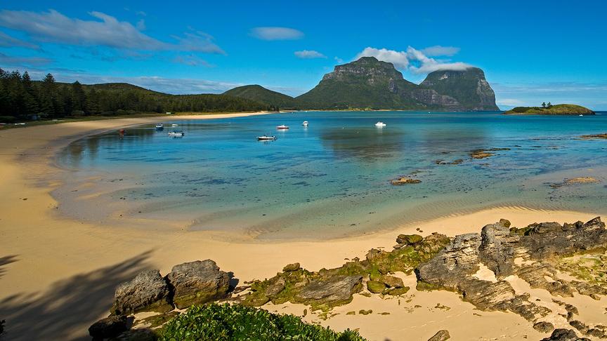 Seichte Bucht mit Strand und Blick auf zwei hohe Berge