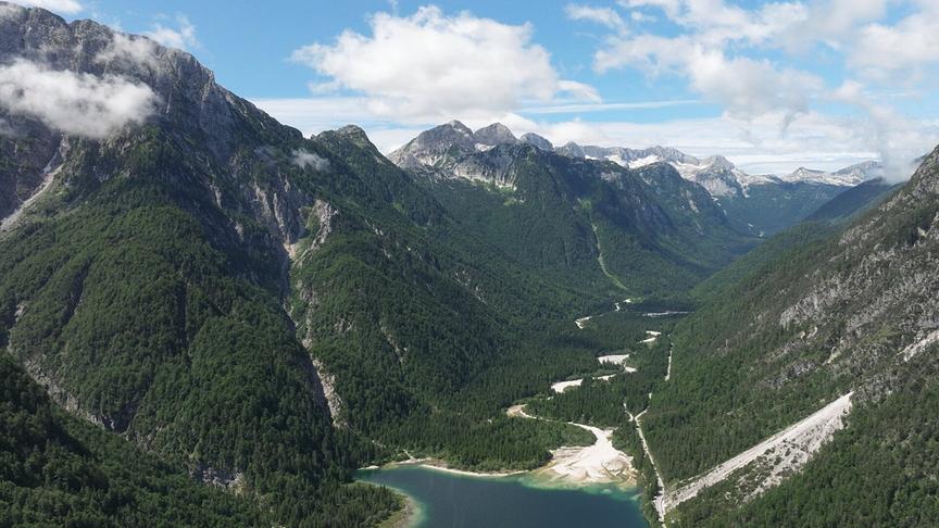 Eine weitwinklige Aufnahme von einer bewaldeten Bergkette und einem Tal, indem ein Fluss fließt.