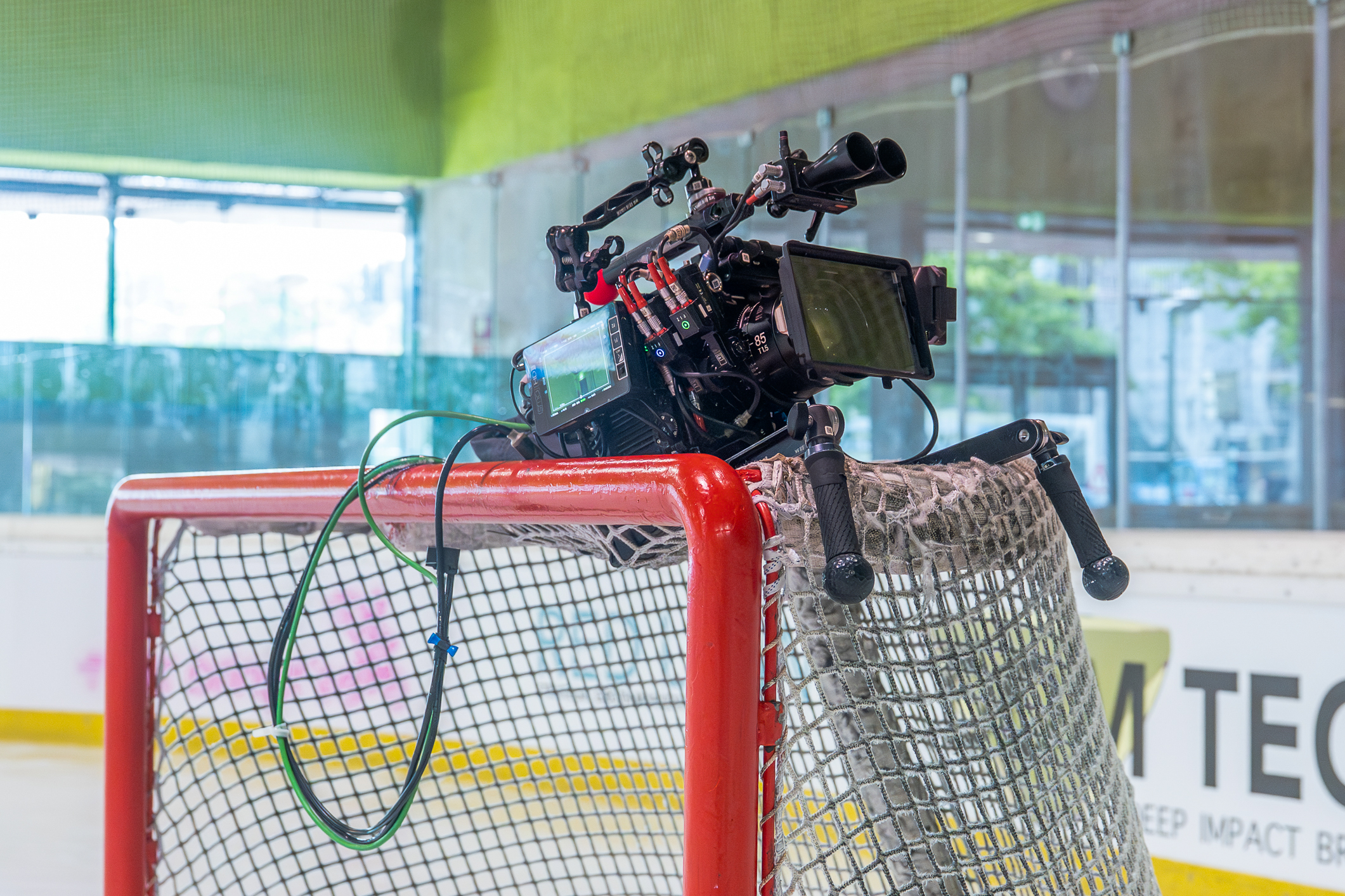 Professionelle Filmkamera ist auf dem roten Tor eines Eishockeyfelds befestigt.