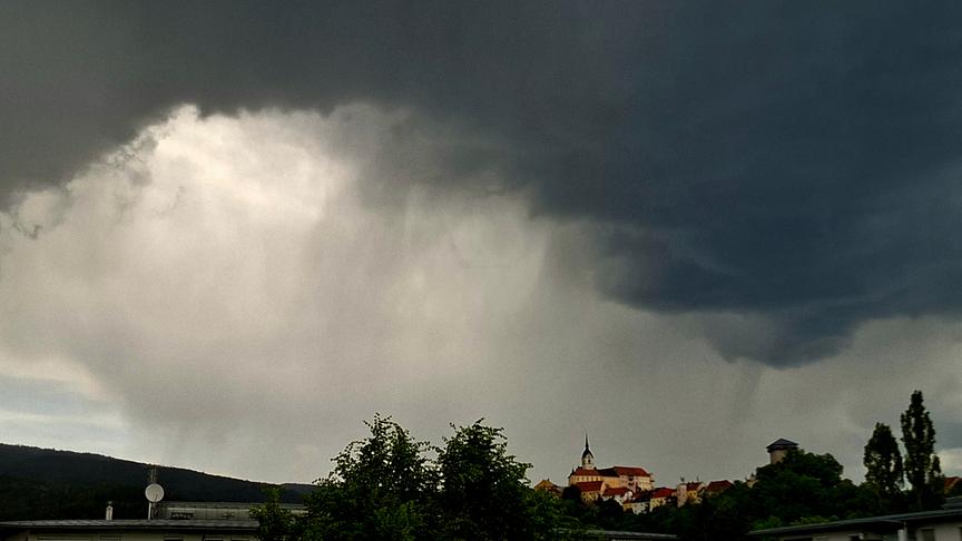 Gewitterstimmung mit dunklen Wolken und Regenschlieren über einer Kirche.