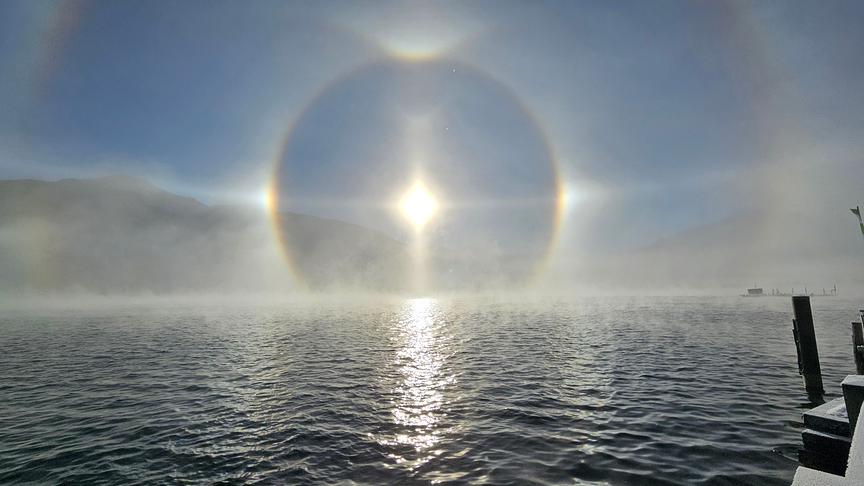 © Johann Wallner Die Sonne mit Halo-Effekt über sich wellendem Wasser eines Sees