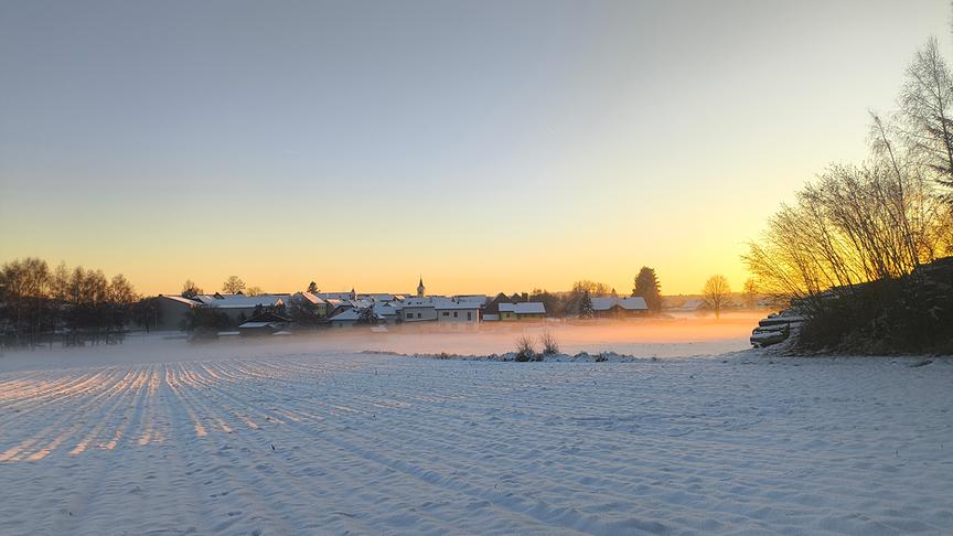 © Gerald Preißl Über einen mit Schnee bedeckten Acker erstrecken sich Sonnenstrahlen