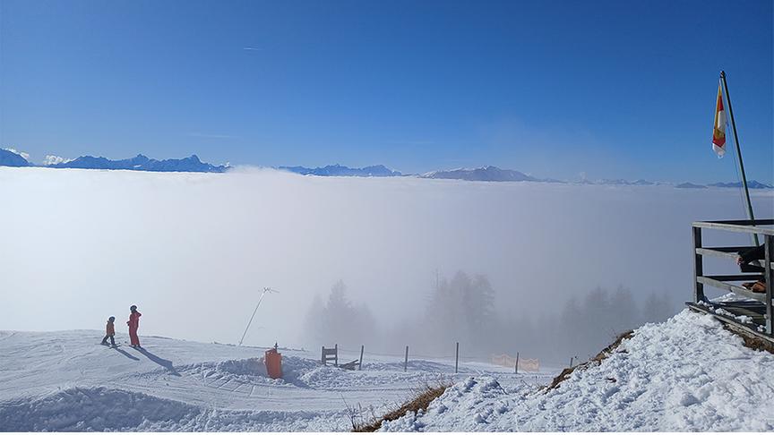 Blick von der Skipiste auf blauen Himmel und darunter verlaufendem dichten Nebel.