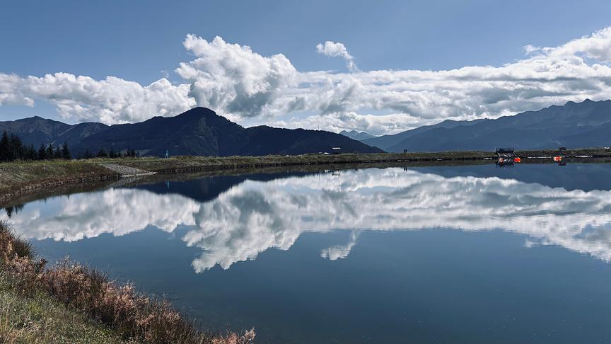 Im hochgelegenen Speicherteich spiegelt sich der blaue Himmel und Wolken.