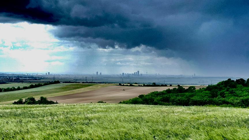 Von der Ferne fotografiertes Wien über dem Regenschauer und dunkle Wolken stehen.