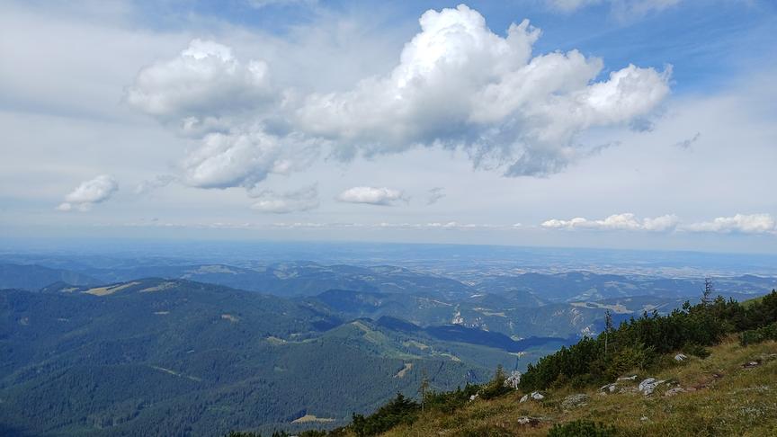 Blick vom Ötscher Richtung Norden, am Himmel einige Wolken, die Schatten auf die hügelige Landschaft werfen.