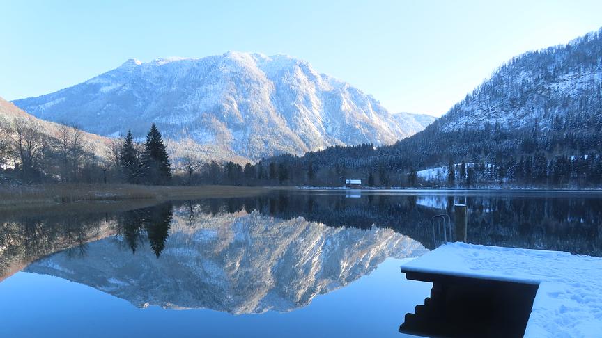 © Rudolf Kößl Im See spiegelt sich der Berg. Der Steg in den See ist schneebedeckt.