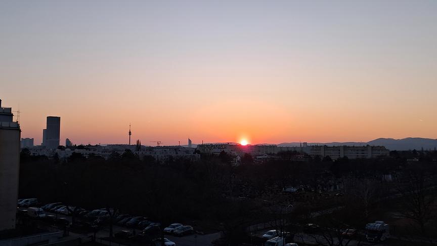 Rot-oranger Sonnenuntergang über Wohngebäuden, im Hintergrund der Milleniumtower