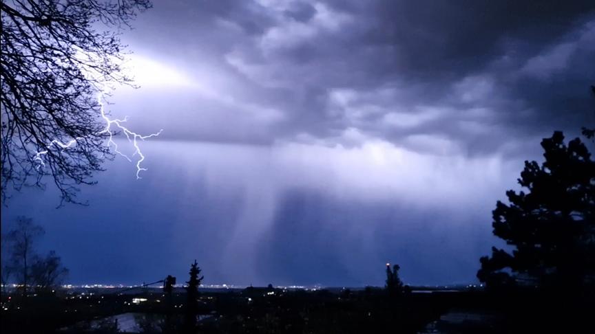 Dunkler Himmel mit zum Boden schleiernden Wolken werden von Blitzen aufgehellt