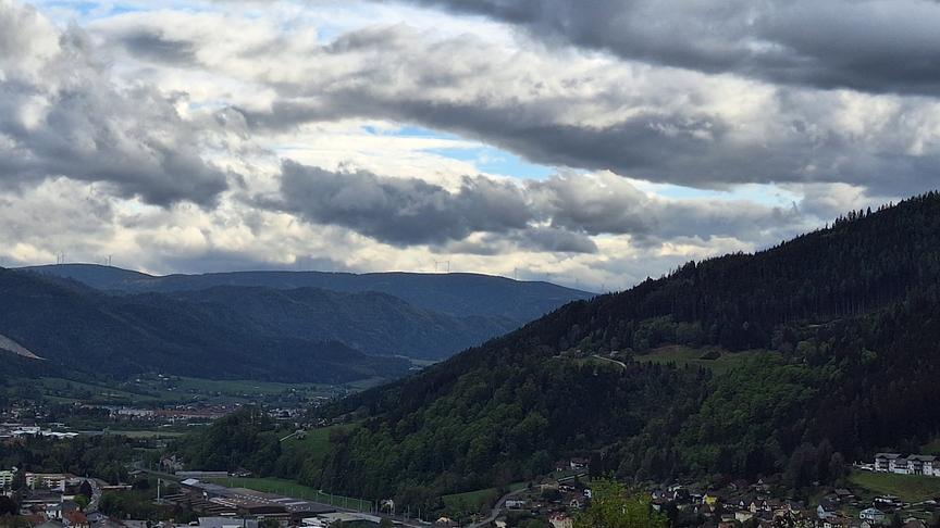 Über dem Tal zwischen bewaldeten Bergen ziehen Wolken auf und verdunkeln die Stimmung. 