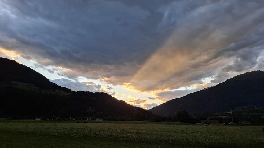 © Erna Linder Zwei Berghänge fallen ab und überschneiden sich etwas. Dazwischen scheinen unter der geschlossenen Wolkendecke deutlich Sonnerstrahlen hervor und erhellen die Wolken von unten etwas.