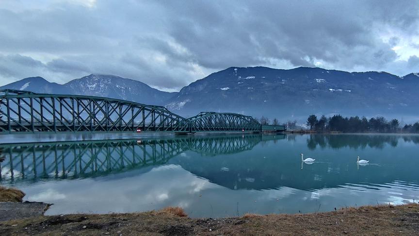 © Ernst Koraschnigg Blick über die Drau mit den zwei Schwänen zu den Karawanken im Hintergrund. Links im Bild die kürzlich restaurierte Eisenbahnbrücke über die Drau. (Ernst Koraschnigg)