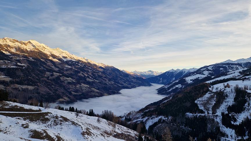 © Julian Reiter Die Nebeldecke verdunkelt noch das Tal, aber die Gipfel des Bergpanoramas werden bereits von der Sonne angestrahlt.