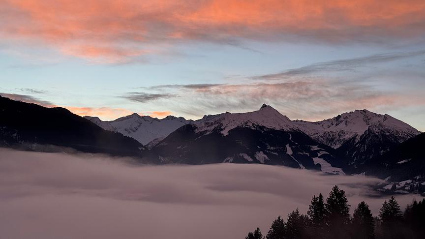 © Martin Löbl Die Wolkendecke hängt zwischen den schneebedeckten Berghimmel bei Sonnenaufgangsstimmung.