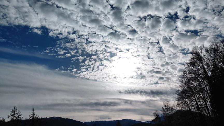 Links: Schleierwolken, rechts: Schäfchenwolken durch die die Sonne hindurchscheint