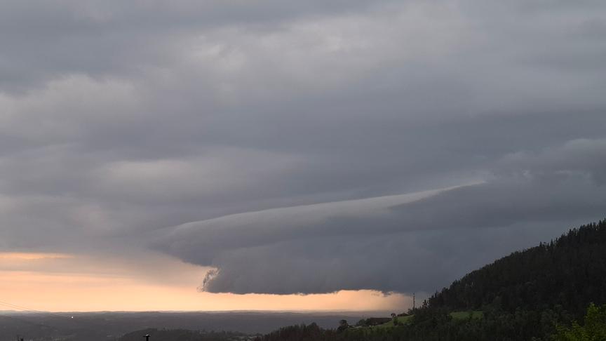 Dunkle, graue Wolkenformation über einem noch hellen Lichtstreifen am Himmel.