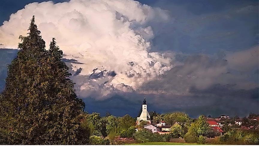 Hohe Wolkenformationen über einem Ort mit Kirche.