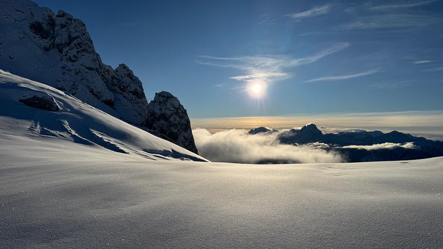 Noch unberührte Schneedecke am Berg, die von der tiefstehenden Sonne erleuchtet wird