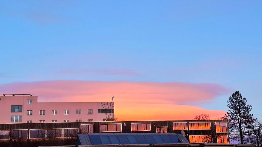 Häuser in der Abenddämmerung, eine orange-rötliche, interessante Wolkenformation dahinter