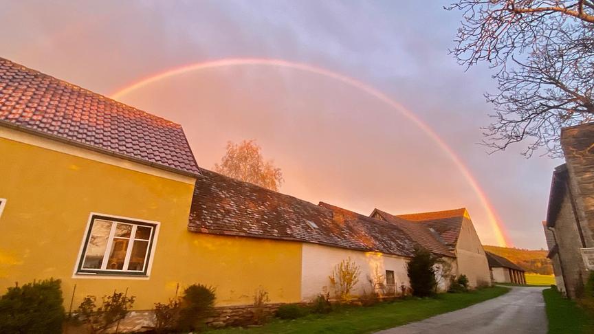 Regenbogen in der Dämmerung über Häusern.