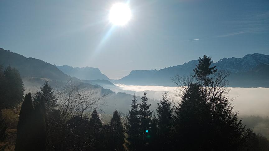 © Beatrice Ziller Blick hinab in ein Tal, das von einer durchgehenden Wolkendecke überzogen ist und von Bergen umgeben. Über der Wolkendecke scheint die Sonne, die Luft wirkt dennoch etwas dunstig/milchig.