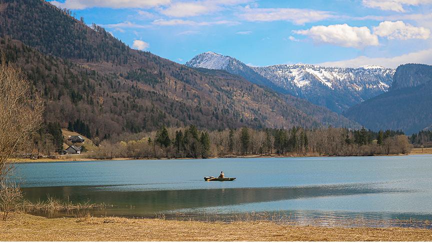 Einsames Padelboot auf einem See umgeben von Bergen