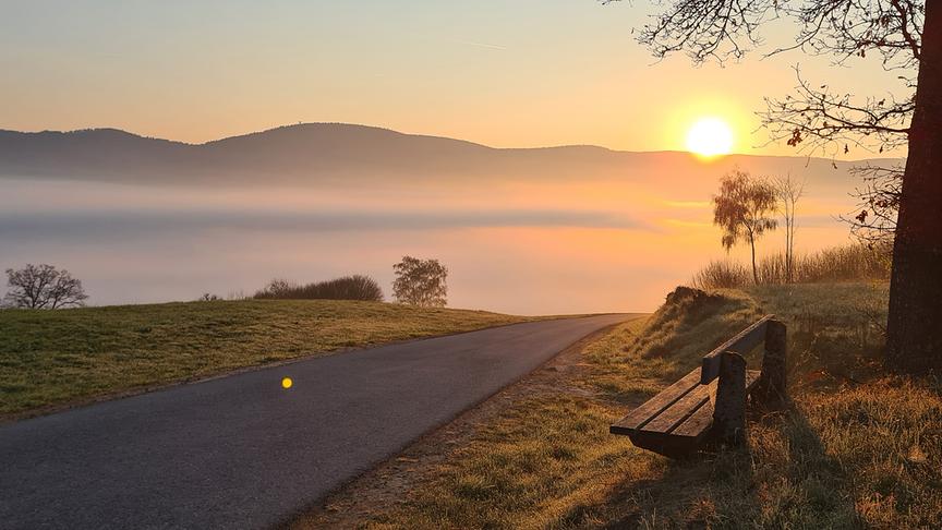 Sonnenaufgang über Hügelkette und Neben im Tal.