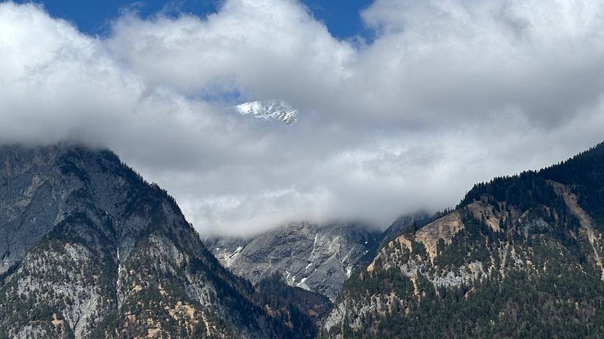 Berg zwischen denen die Wolken hängen.