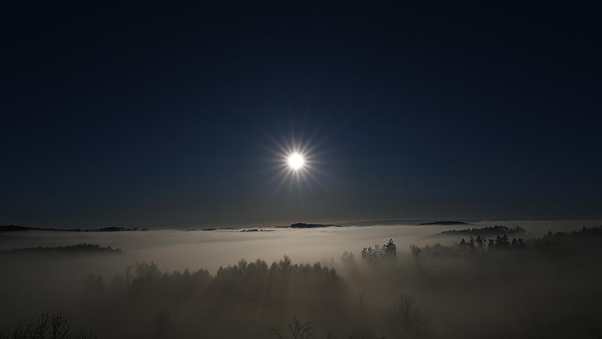 Die Sonne strahlt über eine Nebeldecke hinweg.