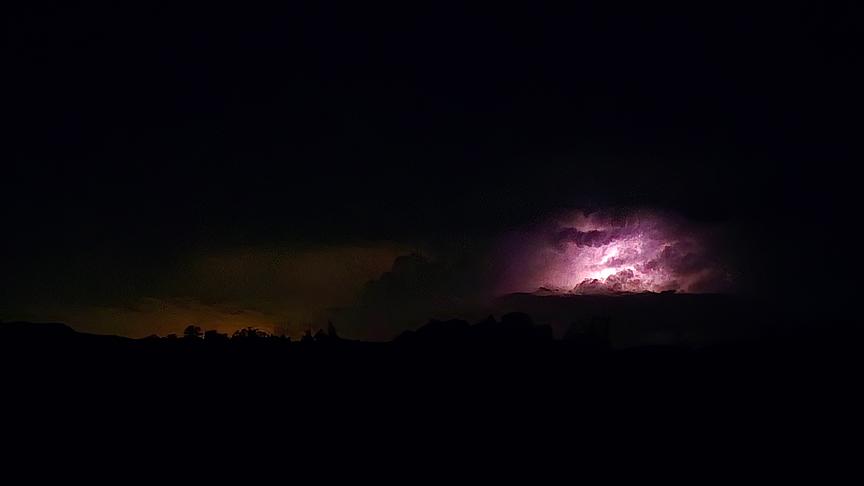Fast vollständige Dunkelheit bis auf eine Wolke, die von innen heraus durch einen Blitz erleuchtet wird.