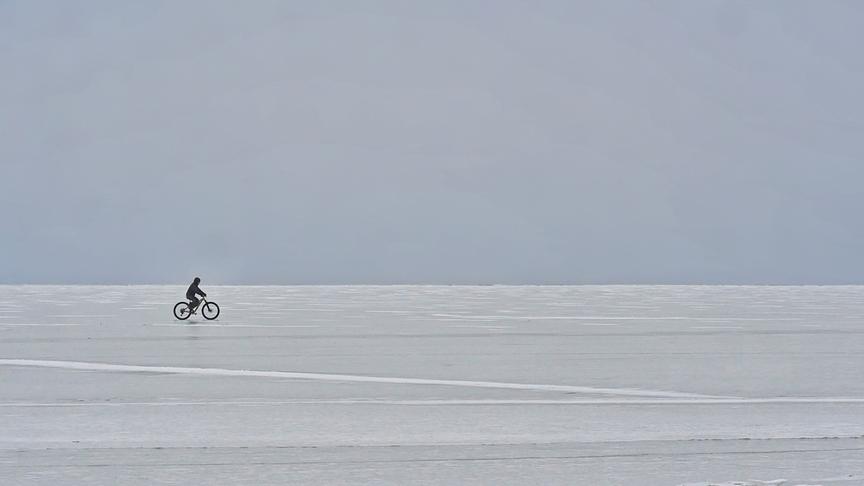 Einsamer Radfahrer fährt über den zugefrorenen See