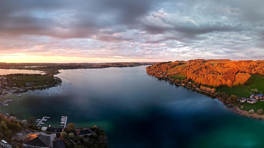 Graue Wolkendecke über einem See bei Dämmerung.