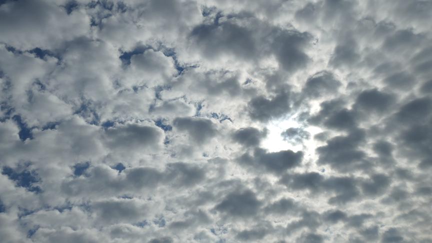 Wolkendecke aus vielen kleineren Wolken, hinter denen die Sonne hervorscheint