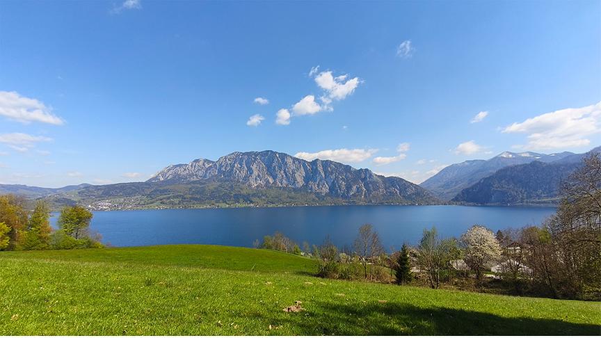 Blick auf See und Berge bei schönem Wetter mit blauen Himmel und nur vereinzelt Wolken.