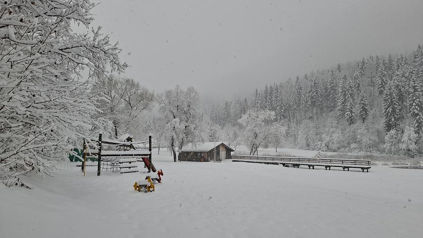Völlig von Schnee eingedeckter Spielplatz, Bäume und Wald.