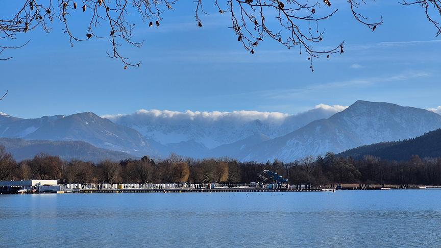 Eine Wolkendecke staut sich sichtbar an den Bergkämmen an, während der restliche Himmel noch blau ist.