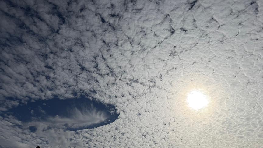 Schäfchenwolken mit Wolkenloch und Sonne