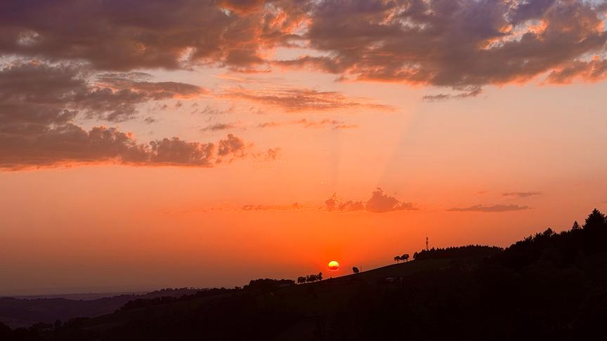 Sonnenuntergang taucht den Himmel und Wolken in orange-rotes Licht