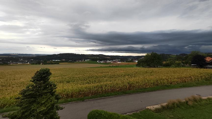 Dunkle Wolken ziehen über einer weiten Landschaft auf.