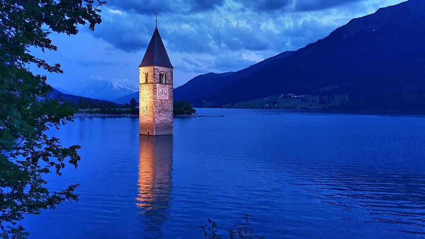 © Manfred Polansky Nur der Kirchturm im Reschensee erinnert an das versunkene Dörfchen Graun. Dahinter trohnt König Ortler mit einem Wolkenhäunchen. (Manfred Polansky)