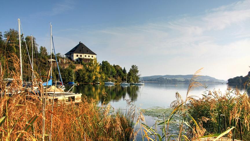 Idyllische Seelandschaft mit Segelbooten, Schilf und dem Schloss Mattsee am Ufer